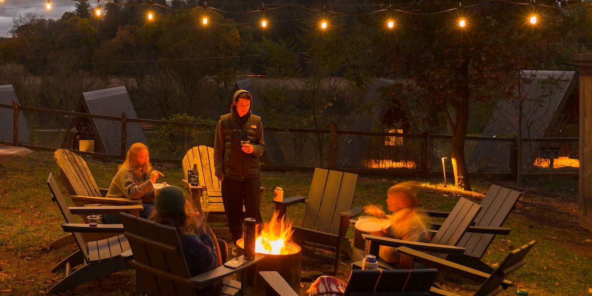 People sitting around a fire pit at dusk.